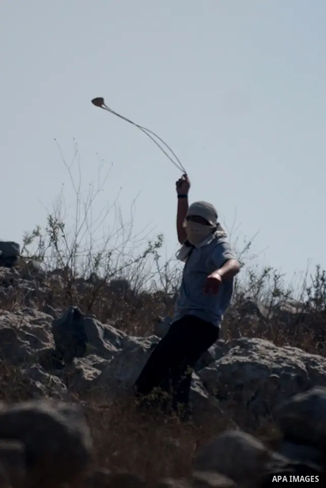 Jewish settlers sling rocks towards Palestinians during clashes close to the northern West Bank village of Burin on July 26, 2010, which began when Israeli troops removed two mobile homes set up near the Bracha settlemen...