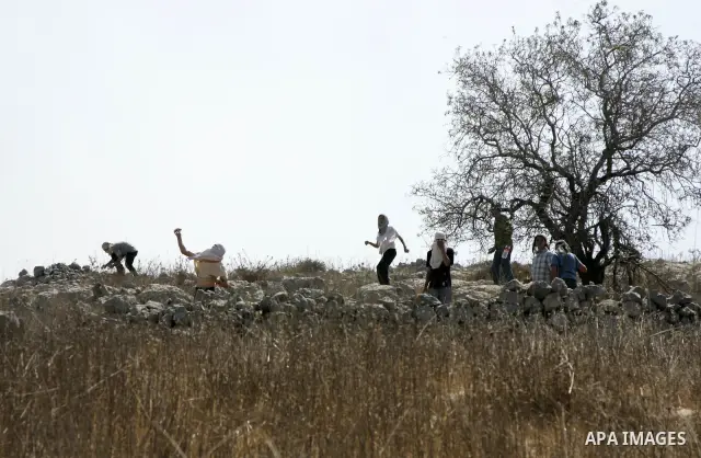 Jewish settlers sling rocks towards Palestinians during clashes close to the northern West Bank village of Burin on July 26, 2010, which began when Israeli troops removed two mobile homes set up near the Bracha settlemen...