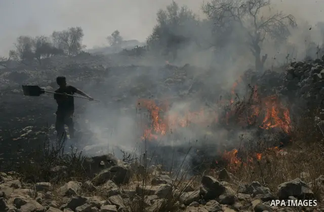 A Palestinian extinguishes fire started by Israeli settlers during clashes close to the northern West Bank village of Burin on July 26, 2010, which began when Israeli troops removed two mobile homes set up near the Brach...