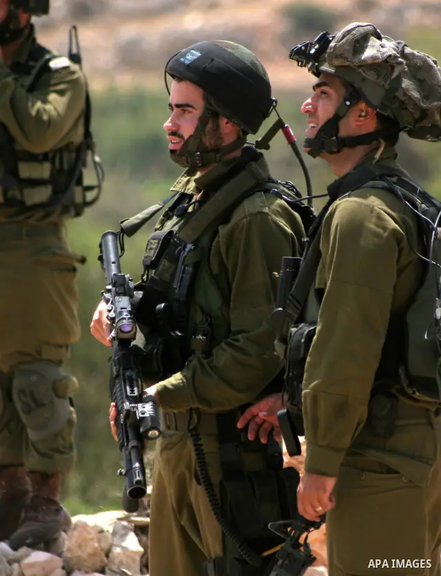 Israeli soldiers stand guards as Palestinian and foreign protesters take part in a demonstration against Israel's controversial separation barrier in the village of Beit Omar near Jewish settlement of Karmi zur near the...
