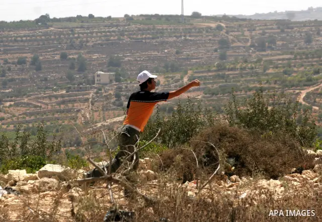 A Palestinian boy uses slingshot to throw stones at Israeli soldiers during a demonstration against Israeli settlements, in the West Bank village of Beit Omar, near Hebron, Saturday, on August 7, 2010.. Photo by Mamoun W...