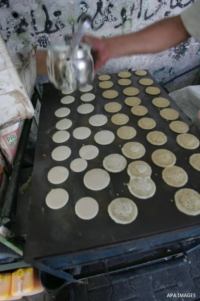 A Palestinian baker makes small traditional pancakes on the first day of the holy month of Ramadan in Rafah in the southern Gaza Strip on August 11,2010. Muslims all over the world fast from dawn to dusk during the holy...
