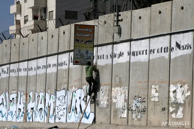 A Palestinian man climbs a ladder to cross Israel's separation barrier on his way to attend prayers in the Al-Aqsa Mosque compound in Jerusalem, in the West Bank town of Al-Ram, just outside Jerusalem, Friday Aug. 13, 20...