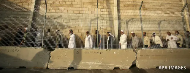 Palestinian Muslim men wait to cross the Isreali controlled Qalandia checkpoint on the outskirts of the West Bank city of Ramallah on August 13, 2010 to reach the Al-Aqsa mosque compound in Jerusalem's old city and atten...