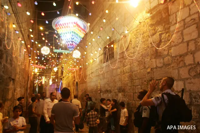 Palestinians walk under colored lights as they go to the evening prayers "Taraweeh" at the al-Aqsa mosque at Jerusalem's old city Damascus Gate after breaking the fast on the thirteenth day of the Moslem holy month of Ra...