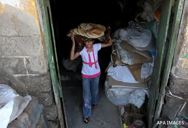 A Palestinian girl carrying loaves of bread at traditional bakery in Gaza City on August 29,2010 . Photo by Ashraf Amra