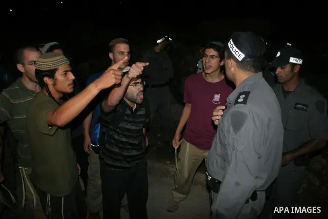 Israeli settlers express their anger in front of Israeli policemen after a settlers car was ambushed by Palestinian gunmen killing two woman and two men next to Kiryat Arba settlement in the southern West Bank August 31,...