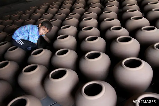 A Palestinian boy is standing in the middle of the earthenware vases at a pottery workshop in Gaza City on Sept 2, 2010. Pottery is a very ancient and traditional industry in Gaza City. Photo by Ashraf Amra