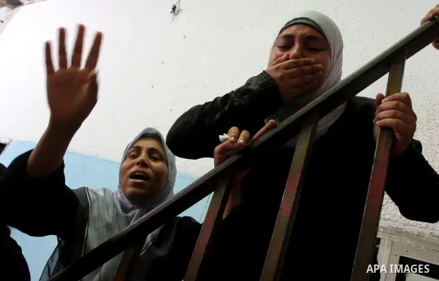 Palestinian women watch as the body of Suleiman al-Hatab, 22-years-old, one of two Palestinian men killed, is taken away from his home during his funeral in the al-Bureij refugee camp in the central Gaza strip, on Septem...