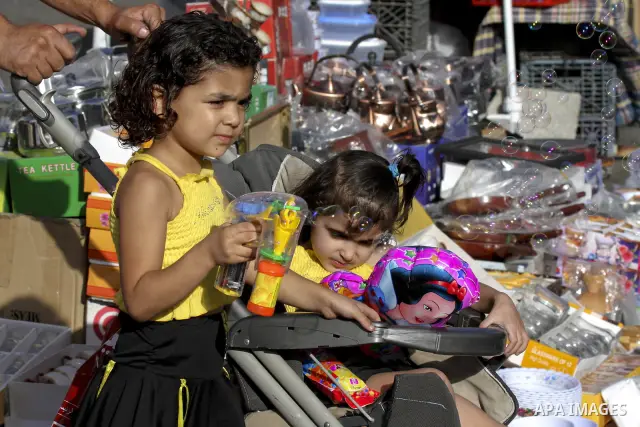 A Palestinian girl plays with a toy at an outdoor market during preparations for Eid el-Fitr holiday, which marks the end of the holy Muslim fasting month of Ramadan, in the West Bank city of Ramallah, Tuesday, Sept. 7,...