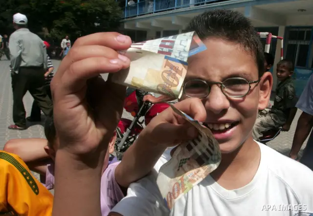 Palestinian primary school children display bills of 100 New Israeli Shekels (23.5 USD) at their school in Rafah, southern Gaza Strip, on Sept 8, 2010. The money was donated by the United Nations Relief and Works Agency...