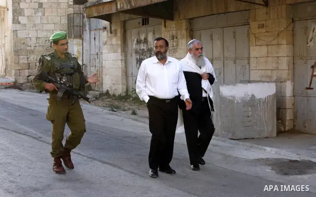 Israeli settlers walk past police guard to the Tomb of the Patriarchs for morning Rosh Hashana (Jewish New Year) prayers, on Sept. 10, 2010, in the West bank town of Hebron, where Palestinian Muslims also pray at the sit...
