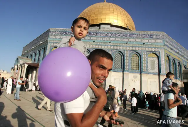 Palestinian kid holds a balloon in courtyards of the Dome of Rock Mosque during the first day of Eid al-Fitr which marks the end of the Muslim fasting month of Ramadan, in the Al Aqsa Mosque Compound in Jerusalem's Old C...