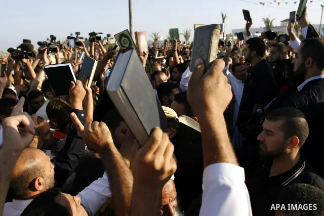Palestinian men hold up the Quran, Islam's holy book, in reaction to a small American church's plan to burn copies of the Quran during a prayer as part of tradition during the first day of Eid al-Fitr which marks the end...