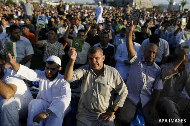 Palestinian men hold up the Quran, Islam's holy book, in reaction to a small American church's plan to burn copies of the Quran during a prayer as part of tradition during the first day of Eid al-Fitr which marks the end...