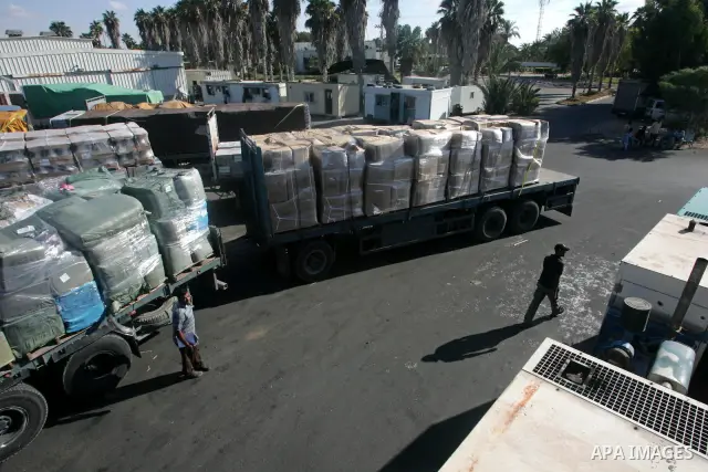 Palestinian men inspect trucks loaded with goods, construction materials and electrical equipments arriving from Israel through the Kerem Shalom border crossing into Rafah, southern Gaza Strip, Monday, Sept. 14, 2010. Is...