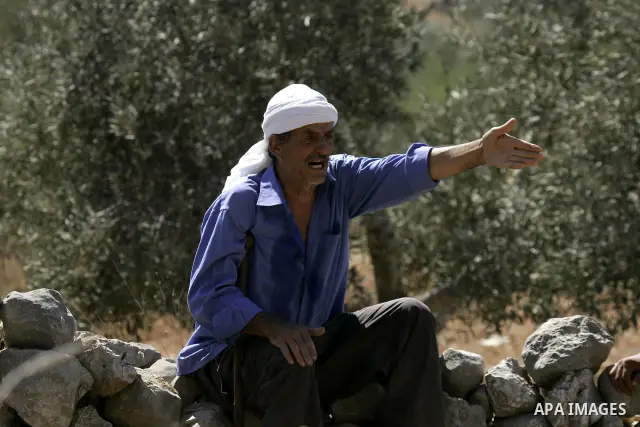 Israeli soldiers prevent Palestinian farmers and Israeli settlers from fighting after a farmer was wounded by Israeli settlers from the Bracha settlement who were trying to collect olives from Palestinian land, on Sept....