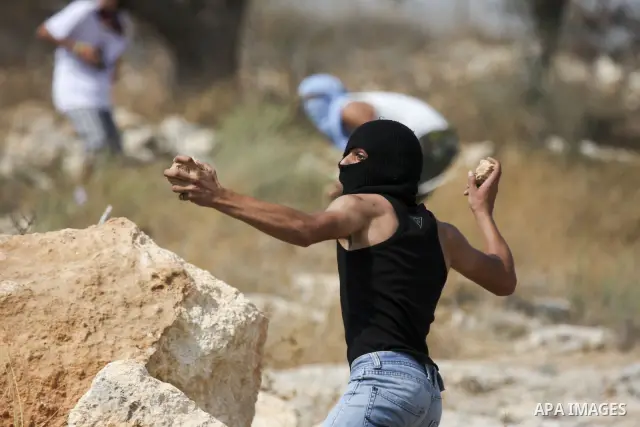 A Palestinian youth hurls stones at Israeli forces during the clashes following a weekly demonstration against Israel's separation barrier in the West Bank village of Bilin, near Ramallah, on September 24, 2010. Photo by...