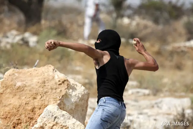 A Palestinian youth hurls stones at Israeli forces during the clashes following a weekly demonstration against Israel's separation barrier in the West Bank village of Bilin, near Ramallah, on September 24, 2010. Photo by...