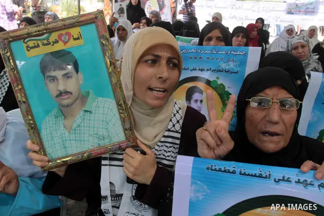 Palestinians women and children hold pictures of relatives held in Israeli jails during a protest against the Israeli assaults on Palestinian prisoners and to demand their release , in Gaza City on Sept. 25,2010 . Photo...