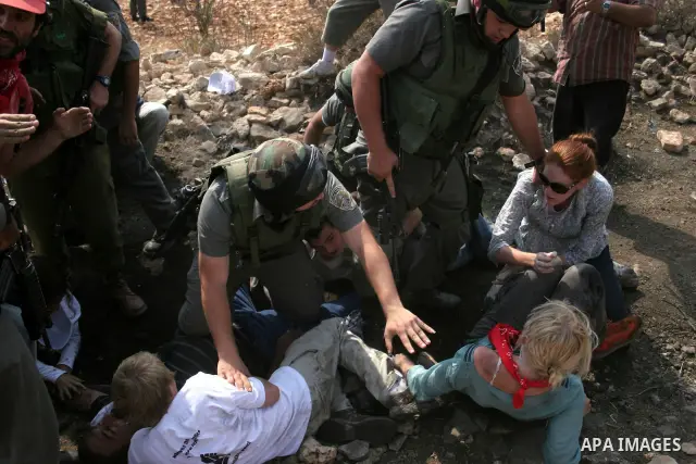 Israeli forces carry away a protester during a demonstration by Palestinian, Israeli and foreign activists against Israel's controversial separation barrier in the West Bank village of Beit Omar, near Hebron, on 25 Septe...