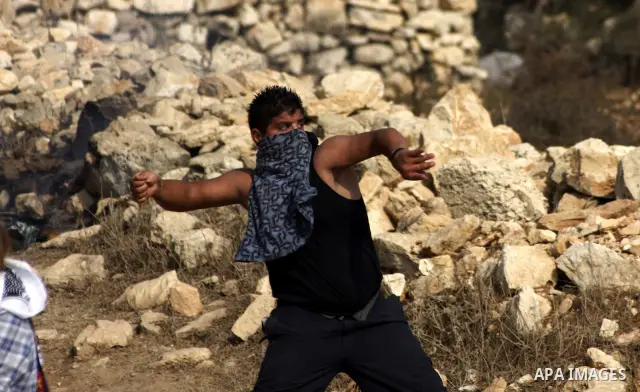 A Palestinian protester hurls stones at Israeli forces during a demonstration by Palestinian, Israeli and foreign activists against Israel's controversial separation barrier in the West Bank village of Beit Omar, near He...