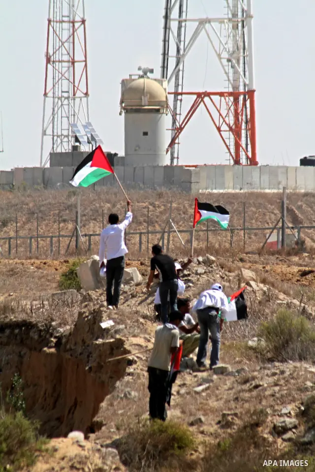 Palestinians hold Palestinian flags during a demonstration against the blockade on Gaza, near the border between Gaza and Israel outside the Maghazi refugee camp, central Gaza Strip, Sunday on Sept. 26, 2010. Israel and...