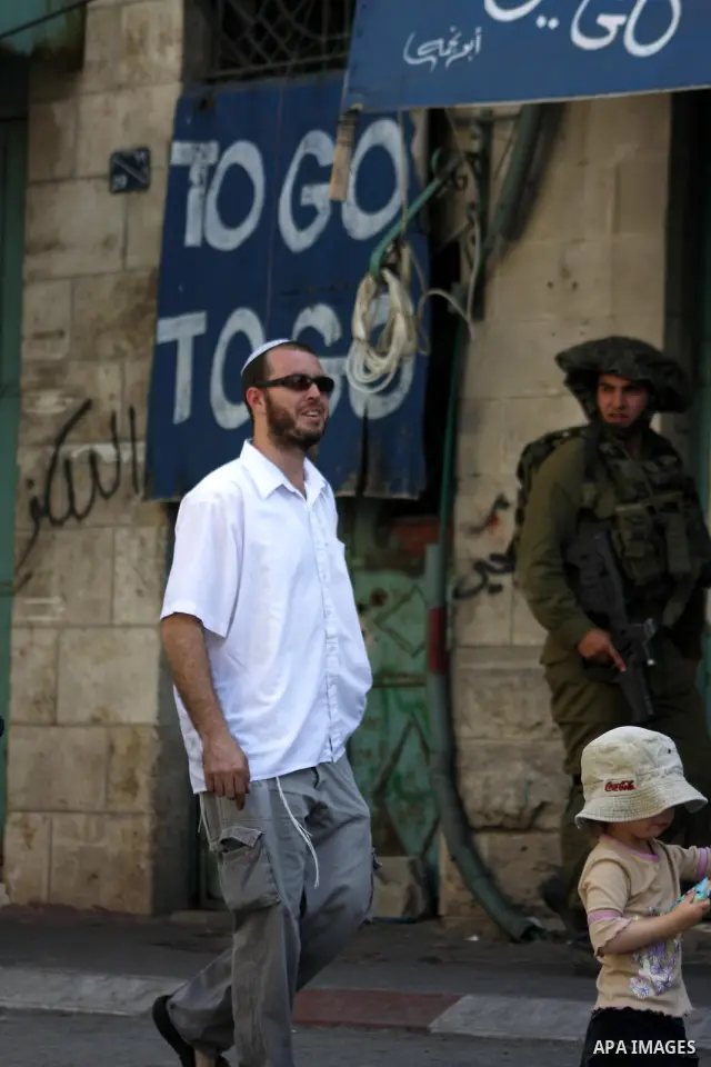 Israeli settlers are escorted by Israeli troops inside the old city of the West Bank town of Hebron on 26 September 2010. A large group of right-wing Jews toured the area with Israeli soldiers escort on the day when the...