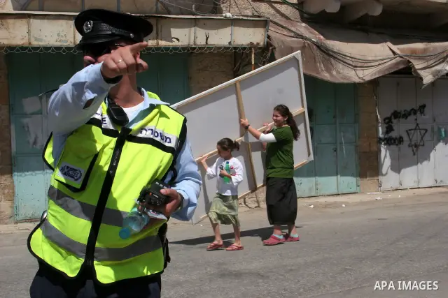 Israeli settlers are escorted by Israeli troops inside the old city of the West Bank town of Hebron on 26 September 2010. A large group of right-wing Jews toured the area with Israeli soldiers escort on the day when the...