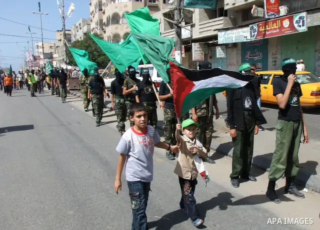 Palestinian children walk past Hamas militants during a rally marking the 10th anniversary of Al-Aqsa Intifada 'uprising' and against peace talks with Israel in the Central Gaza Strip on October 1, 2010 . Photo by Wassim...