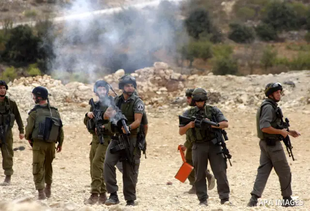 Israeli soldiers stand guard during a demonstration by Palestinian, Israeli and foreign activists against Israel's controversial separation barrier in the West Bank village of Beit Omar, near Hebron, on Oct. 2,2010. Isra...