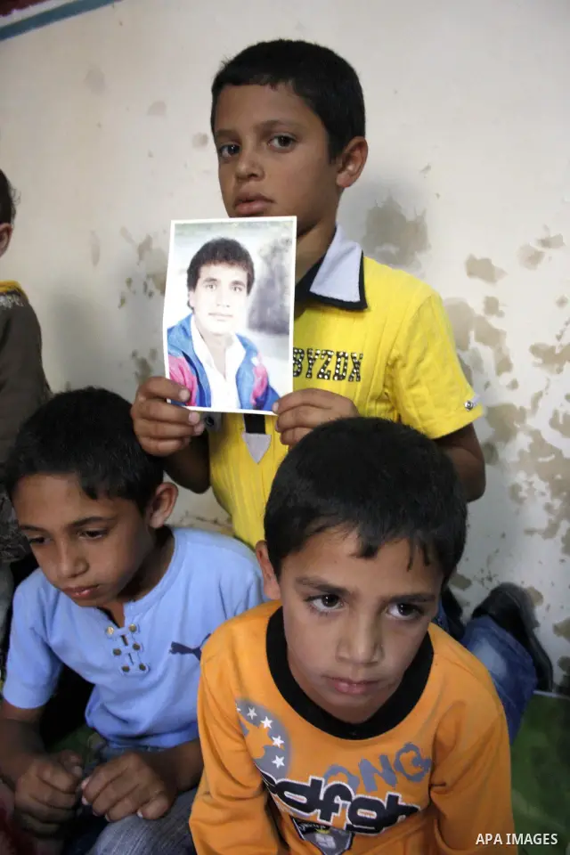 The son holds the photographer of her killed father Ezzedine Kawasba, 38, as his mother and youngest brother sit by during his funeral in the Israeli occupied West Bank village of Saair, west of the town of Hebron on Oct...