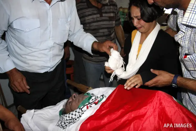 Palestinians mourn at the body of Palestinian Shehda Karaja, 55, during his funeral near the Israeli occupied West Bank city of Hebron on October 4,2010. Karaja was died after a heart attack after being fear and inhaling...