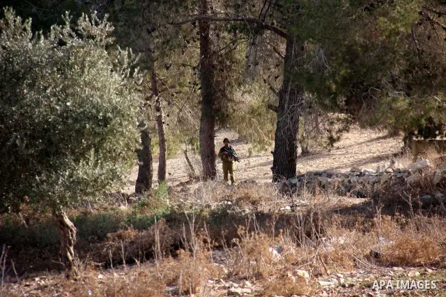 An Israeli soldier stands guard as jewish settlers from the Israeli settlement of Yitzhar demonstrate near the Palestinian village of Burin in the Israeli occupied West Bank, several kilometers from the northern city of...