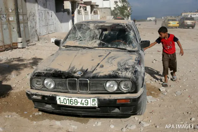 Palestinian boy stands next to a car damaged by an Israeli airstrike, in Gaza City, Thursday, Oct. 7, 2010. Palestinian official said that Israeli aircraft struck Hamas training base for security forces of Gaza's militan...