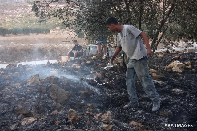 A Palestinian farmer from the village of Hawara uses a water to extinguish fire at his olives tree grove that was allegedly set ablaze by Jewish settlers from the nearby settlement of Yitzhar in the northern West Bank on...