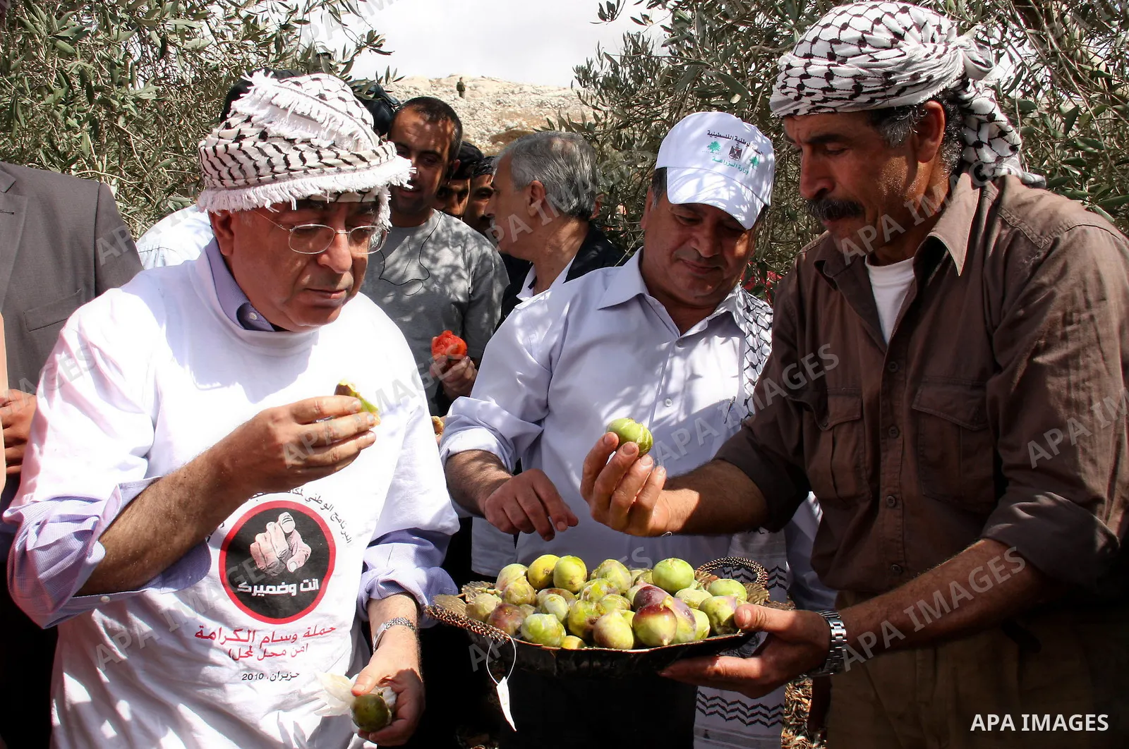 Palestinian Prime Minister Salam Fayyad takes part at a meal to break the daily picks olives as he visits Palestinian farmers during the harvest season in the West Bank village of in Iraq Burin, near Nablus, Saturday, Oc...