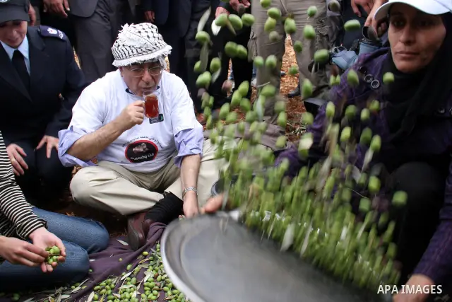 Palestinian Prime Minister Salam Fayyad , watches olives being sorted as he visits Palestinian farmers at the beginning of olive harvest season in the West Bank village of Iraq Burin, near Nablus, Saturday, Oct. 9, 2010...