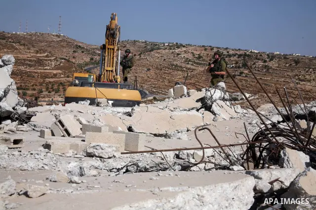 Israeli soldiers stand guard during the demolition operation of a Palestinian house and water wells that belong to Rugby family , just east of the West Bank town of Hebron on October 11,2010 . Photo by Najeh Hashlamoun