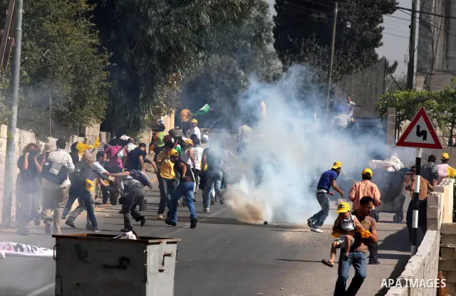 Palestinians and foreign activists run for cover from tear gas canister fired by Israeli soldiers during a demonstration against the expansion of the nearby Jewish settlement of Halamish in the West Bank village of Nabi...
