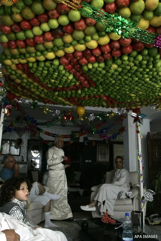 Samaritan family sits under a Sukka, made from fresh fruit and vegetables for the holy day of the Tabernacles or Sukkot, at their most sacred site at Mount Gerizim near the northern West Bank City of Nablus, Friday, Oct....