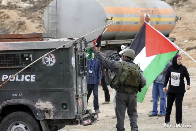 A Palestinian man waves a Palestinian flag during violent clashes in the West Bank village of Nabi Saleh, on 29 October 2010. Palestinians protest weekly against the neighbouring Jewish settlement of Halamish. Photo by E...