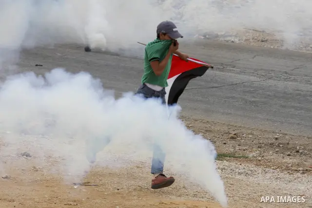 A protester runs for cover as Israeli troops fire tear gas during violent clashes in the West Bank village of Nabi Saleh, on 29 October 2010. Palestinians protest weekly against the neighbouring Jewish settlement of Hala...