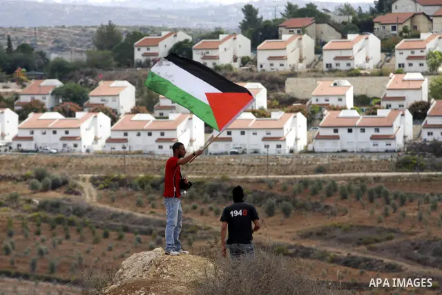 A Palestinian man waves a Palestinian flag during violent clashes in the West Bank village of Nabi Saleh, on 29 October 2010. Palestinians protest weekly against the neighbouring Jewish settlement of Halamish. Photo by E...