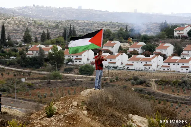 A Palestinian man waves a Palestinian flag during violent clashes in the West Bank village of Nabi Saleh, on 29 October 2010. Palestinians protest weekly against the neighbouring Jewish settlement of Halamish. Photo by E...