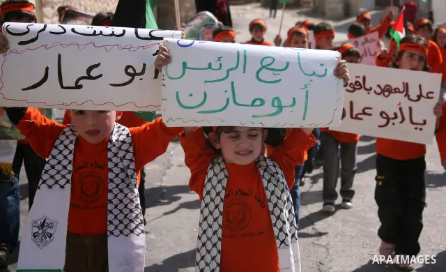 Palestinian childs hold up a placard of the late Palestinian leader Yasser Arafat , Palestinian leader Mahmoud Abbas , wave their national flags and Fatah party flag during a rally commemorating the 6th anniversary of la...