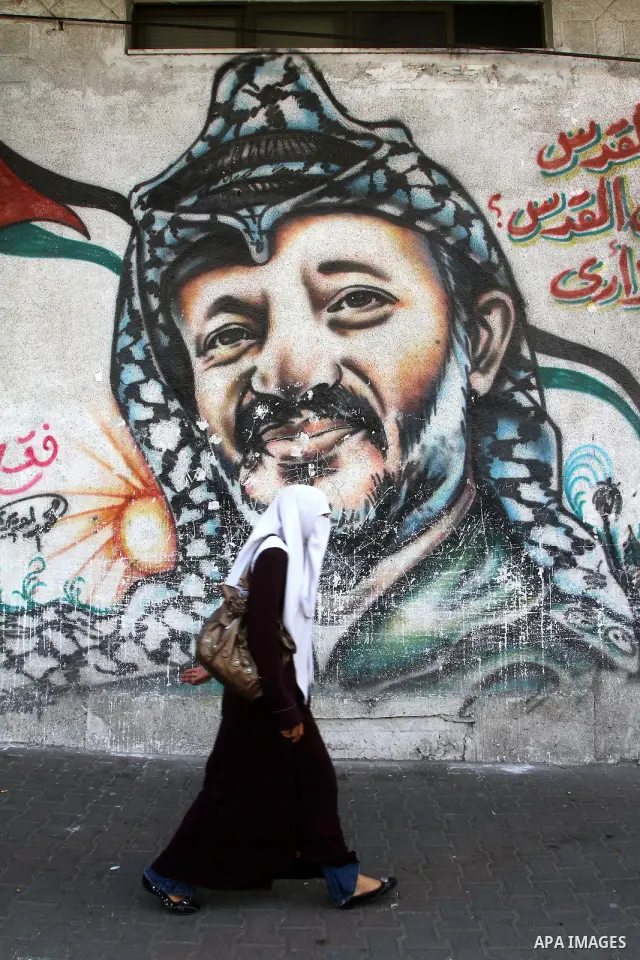 Palestinians walk past graffiti showing late Palestinian leader Yasser Arafat in Gaza City on November 11, 2010, as Palestinians mark the sixth anniversary of his death. Photo by Ashraf Amra