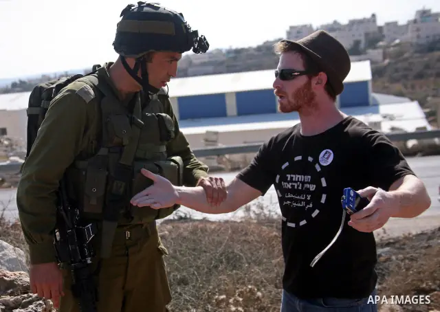 Israeli soldiers argue with a foreign activist during a demonstration by Palestinian, Israeli and foreign activists against Israel's controversial separation barrier in the West Bank village of Maasarah, near Bethlehem o...