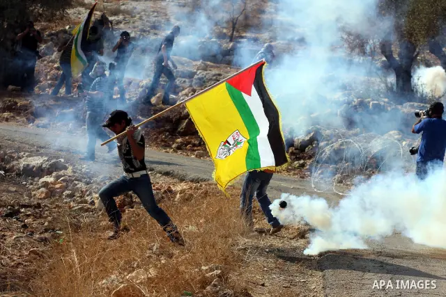 A Palestinian youth runs for cover from tear gas canister fired by Israeli soldiers during a protest against Israel's separation barrier as masked Palestinian stones throwers clash with Israeli soldiers in the West Bank...