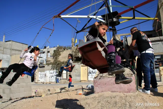 Palestinian refugee children enjoy a ride on swings put up in the Askar refugee camp outside the West Bank city of Nablus ,Wednesday, Nov. 17, 2010. as Muslims worldwide commemorate Eid al-Adha, or the Feast of the Sacri...